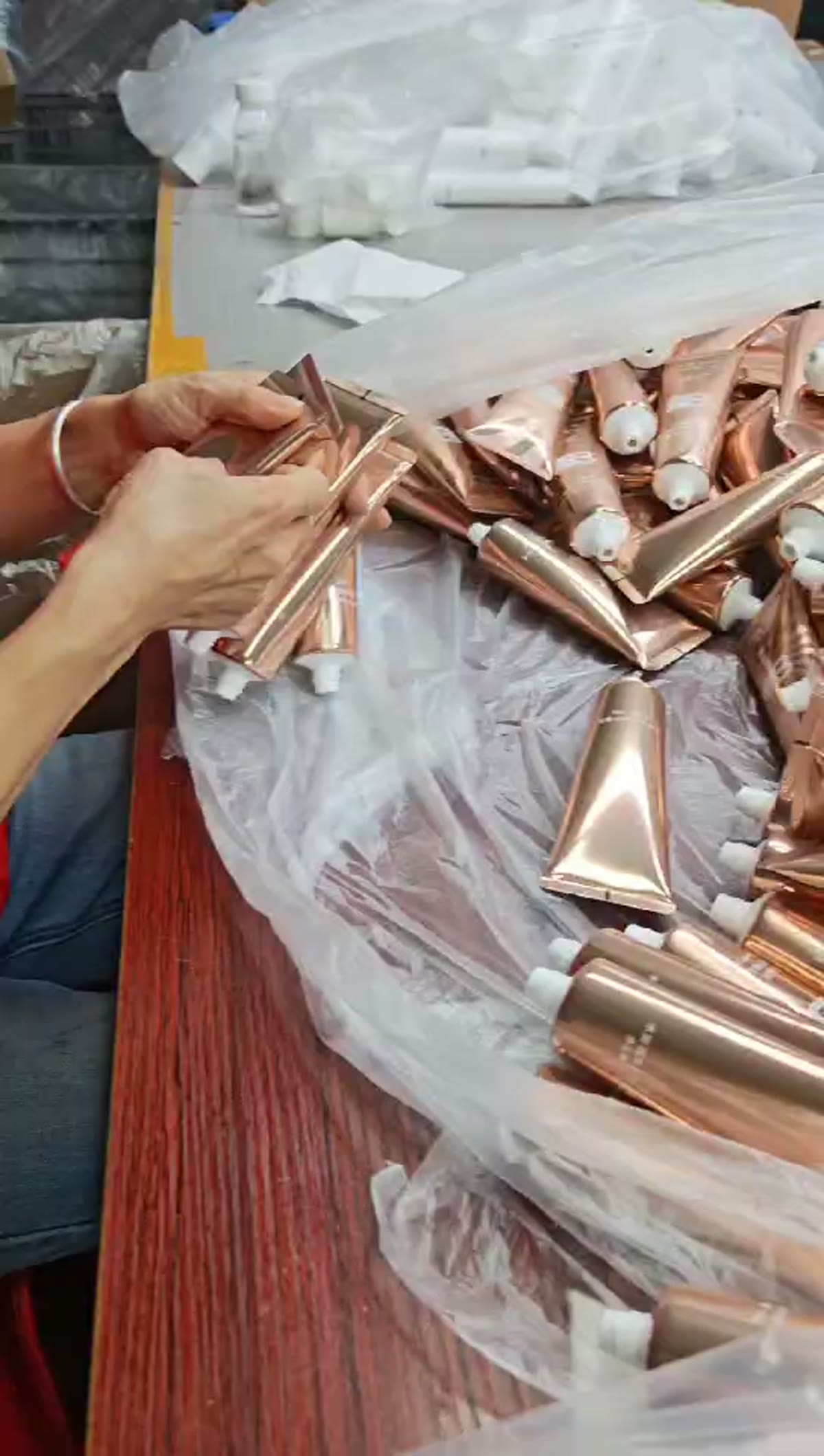 Hands handling cosmetic tube packaging at the factory